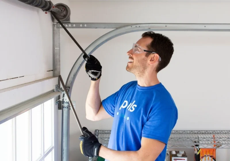 Technician adjusting the torsion spring on a sectional garage door