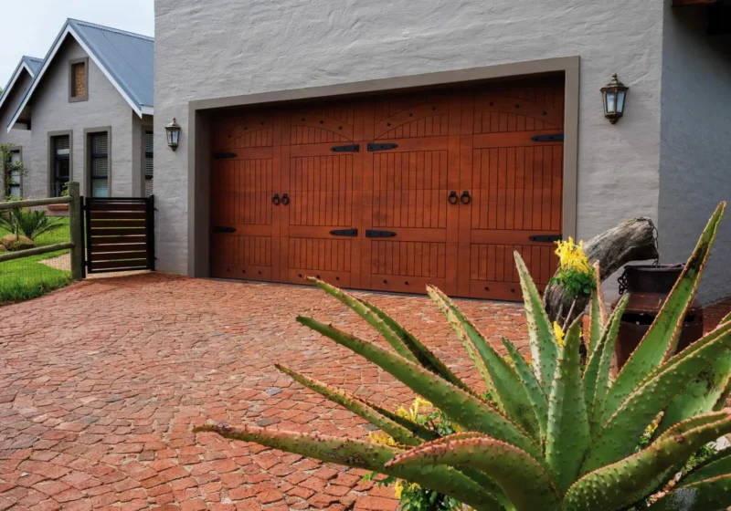 Solid timber garage door with wrought-iron strap hinges on a face-brick home